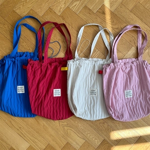 Flat lay of striped drawstring tote bags in blue, red, white and pink on wooden floor