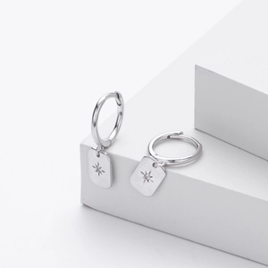 Macro view of S925 silver hoop earrings featuring embossed star rectangular pendants