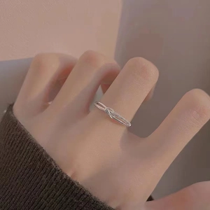 Close-up of a silver knot-shaped ring with pavé settings worn on a model's finger