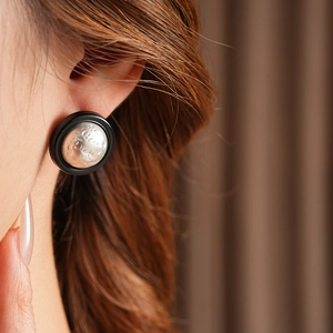Macro detail of round vintage stud earrings featuring black trim and textured silver dome