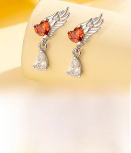 Macro detail of angel wing heart earrings with red zircon and silver titanium steel studs