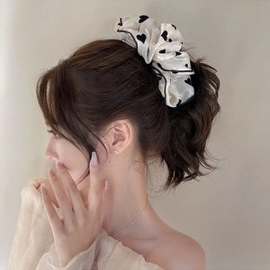 Detail of cream oversized scrunchie with black heart pattern on a low ponytail