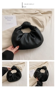 Macro detail of black pleated cloud handbag featuring leather texture and knotted handle