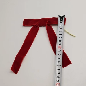 Detail shot of a 20cm red velvet Christmas bow with a measuring tape for size scale