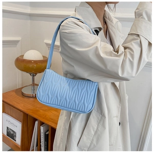 Detail of sky blue leather shoulder bag with wavy texture on beige trench coat