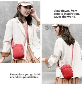 Detail view of a compact red nylon crossbody bag with dual zippers and adjustable strap