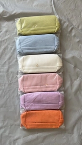 Vertical stack of six colorful corduroy makeup bags in individual clear packaging