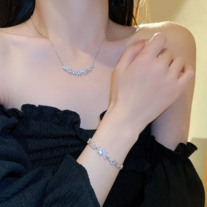 Detail of silver V-shaped necklace and bracelet set with cubic zirconia leaves