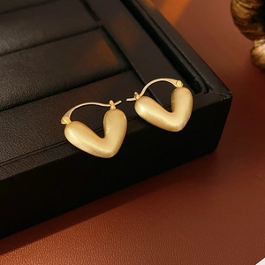 Detailed close-up of matte gold heart earrings with elegant brushed metal texture