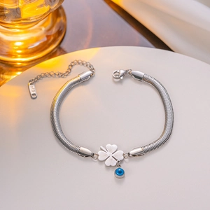 Silver 18KGP snake chain bracelet with clover and blue evil eye charms on white stage