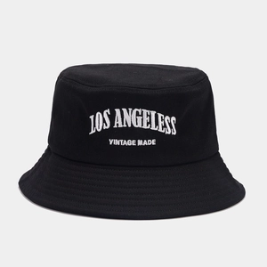 Detail of white vintage embroidery on a black cotton bucket hat with street style texture