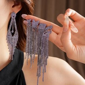 Gros plan de boucles d'oreilles à pompons en strass violets portées par un mannequin