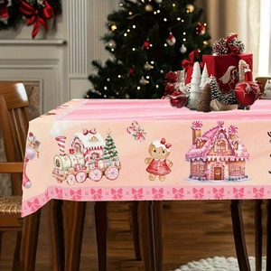 Close-up of pink Christmas tablecloth featuring gingerbread house and festive train patterns
