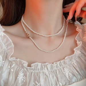 Detail of double-layer white pearl necklace with gold OT buckle on model neck