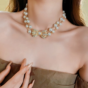 Detail of double-layer pearl necklace with a rhinestone bow pendant on a female model