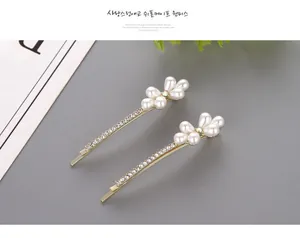 Macro shot of gold-tone bobby pins with white pearls and sparkling rhinestone floral patterns