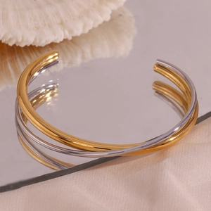Polished double-layer crossover open bangles in gold and silver on a mirror base