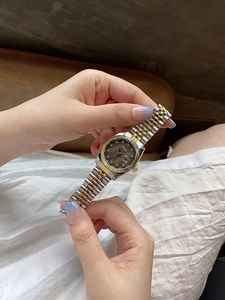 Detail of grey watch dial with diamond markers and calendar window on steel strap