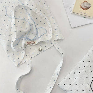 Detail of white canvas tote bag featuring blue heart print and secure metal magnetic clasp