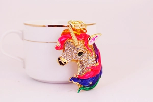 Close-up of a golden unicorn keychain with colorful enamel mane and sparkling rhinestones