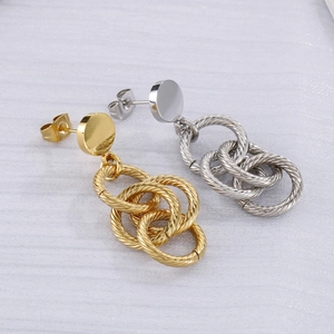 Vue macro de boucles d'oreilles à trois anneaux torsadés en doré et argenté