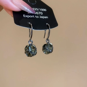 Gros plan de boucles d'oreilles en cristal vert enveloppées de fil d'argent 925