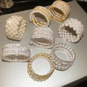 Detail view of multi-layer pearl and rhinestone spiral bracelet in gold and silver finish