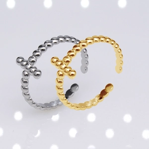 Close-up of gold and silver beaded open rings with T-shaped detail on light background