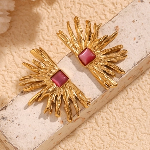 Detailed macro view of 18K gold plated earring with red gemstone and sunburst texture