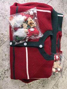 Detail of red Christmas knit cardigan with green trim and festive holiday doll accessories