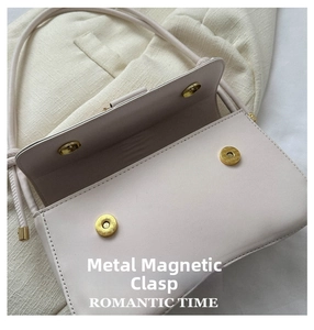 Detail of the high-quality magnetic snap closure on a cream white leather shoulder bag