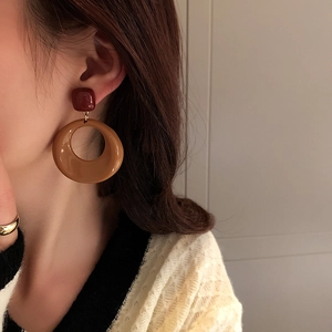 Detail view of vintage geometric acrylic earrings in deep red and caramel on a model
