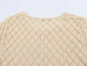 Close-up of beige knit top featuring detailed hollow diamond mesh texture and round neckline