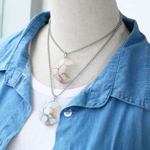 Detail of moon-shaped Tree of Life pendants featuring rose quartz and opal stones