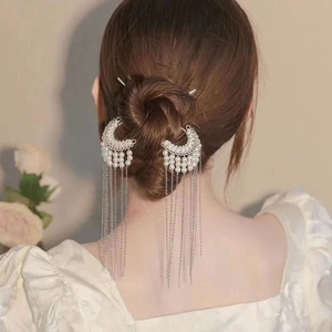 Elegant moon-shaped hair pin with pearls and silver tassels on a braided hairstyle