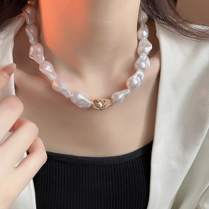 Gros plan d'un collier de perles baroques avec pendentif en métal doré sur un mannequin