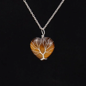 Macro view of silver wire wrapped tree of life on tiger eye heart pendant necklace