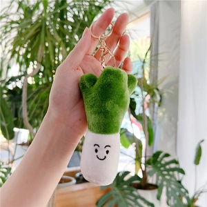Detailed view of a plush scallion keychain with smiling face and golden metal clasp