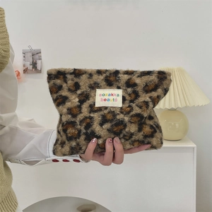 Close-up of leopard print plush cosmetic bag with soft faux fur and brand label