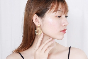 Detail of rose gold geometric triple hoop earrings worn by a model in soft lighting