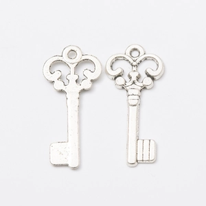 Pair of vintage silver alloy key charms with an antique finish on white background