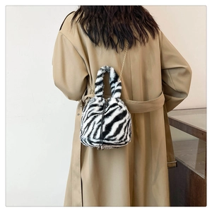 Detail view of zebra print plush bucket bag with golden chain strap and drawstring closure