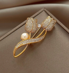 Detailed view of golden tulip brooch featuring white zircons and a round white pearl
