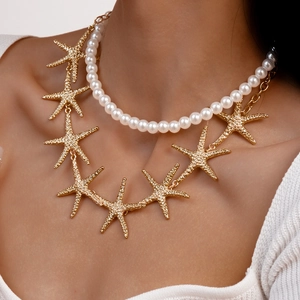 Detail of layered gold starfish charm and white faux pearl choker necklace on neck