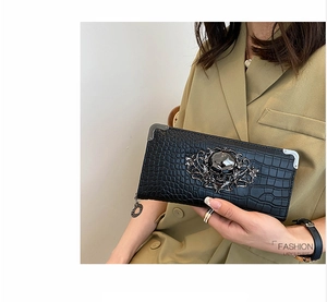 Detail of black crocodile texture lady's purse with gothic metal skull and floral relief