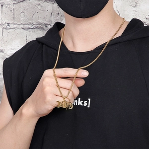 Detail of a gold gothic letter pendant necklace on a stainless steel box chain