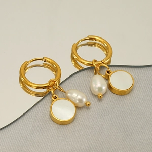 Elegant gold round earrings with white pearl and shell pendants on textured fabric
