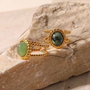 Detailed macro view of vintage gold rings with green natural stones on a stone pedestal