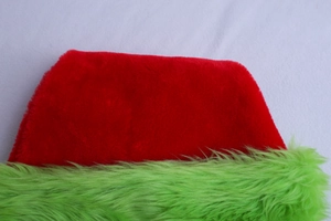 Detail of red plush fabric and green faux fur edge of a creative Christmas hat