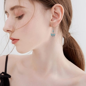 Bohemian turquoise butterfly drop earrings worn by a model in a side profile view